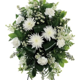 White floral standing spray with daisies and carnations on a black easel