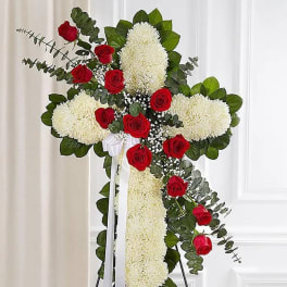 Cross-shaped floral tribute with red roses and white chrysanthemums on an easel