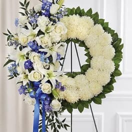 White floral funeral wreath with blue and white flowers on an easel