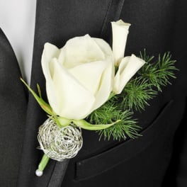 White rose boutonniere with green accents on a black suit lapel