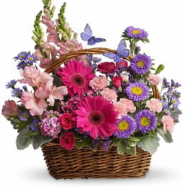 Basket of pink, purple, and magenta flowers with butterfly picks