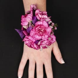 Pink floral wrist corsage on a person's hand