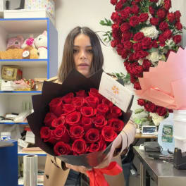 Woman holding a bouquet of red roses wrapped in black paper with a red ribbon