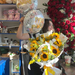 Woman holding a sunflower bouquet and two birthday balloons