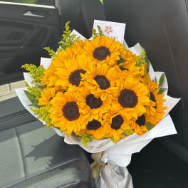 Bouquet of bright yellow sunflowers wrapped in white paper