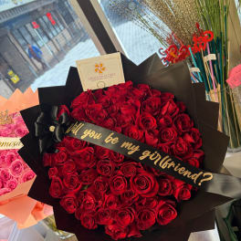 Large bouquet of red roses wrapped in black paper with a ribbon
