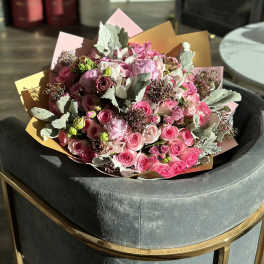 Bouquet of pink roses and pale blooms wrapped in pastel paper
