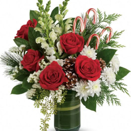Red roses and white flowers in a green glass vase with candy canes