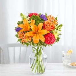 Orange and pink mixed bouquet in a clear glass vase