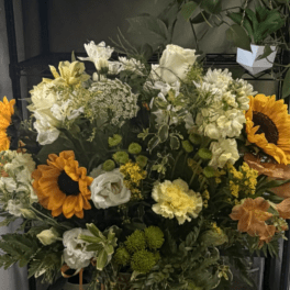Large mixed bouquet in a clear glass vase with sunflowers and white blooms
