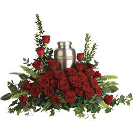 Red roses arranged around a silver urn with greenery