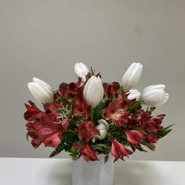 Red alstroemeria and white tulips in a gray vase