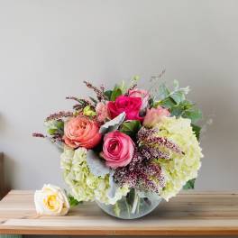 Bouquet of pink and peach roses with pale hydrangeas in a glass vase