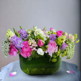 Pink and purple mixed flower arrangement in a green glass vase