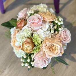 Bouquet of blush and peach roses with white hydrangea and berry accents