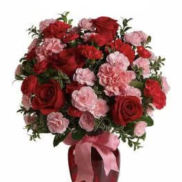 Red roses and pink carnations in a red vase with a pink ribbon