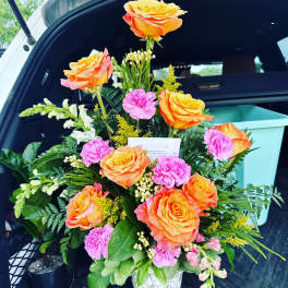 Orange roses and pink carnations arranged in a white vase