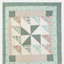 Patchwork quilt with teal, cream, and patterned geometric blocks