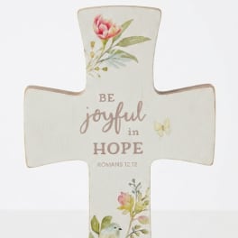 Cross-shaped decorative sign with floral print and the words "Be joyful in hope"