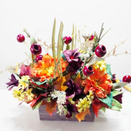 Colorful floral arrangement in a rectangular container with orange, purple, and yellow blooms