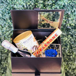 Gift box with a blue rose, champagne bottle, and candy bar