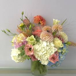 Pastel mixed flower arrangement in a textured glass vase