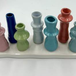 Colorful miniature ceramic vases arranged on a white tray