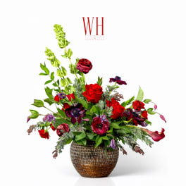 Mixed red and purple floral arrangement in a textured brown vase