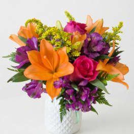 Orange lilies and purple flowers in a white vase with a pink rose