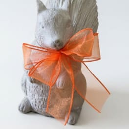 Gray squirrel figurine tied with an orange sheer ribbon