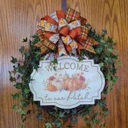 Fall wreath with a pumpkin welcome sign and plaid bow