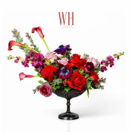 Mixed red and pink floral arrangement in a black pedestal bowl