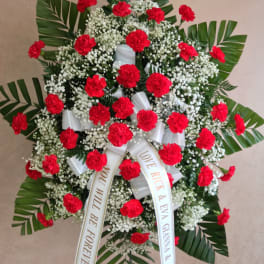Standing wreath of red carnations with white baby's breath and ribbon