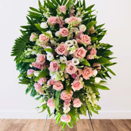 Large standing spray of pink roses and white flowers with tropical greenery