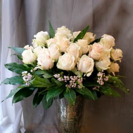 Cream rose arrangement in a tall silver vase