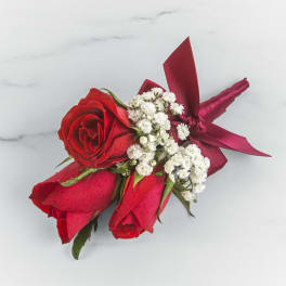 Red rose boutonniere with white baby's breath and a red ribbon