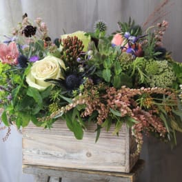 Mixed floral arrangement in a rustic wooden box with cream and pink blooms