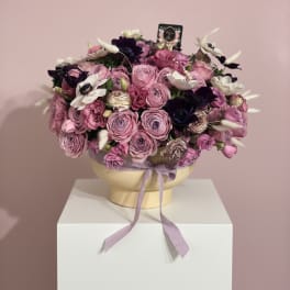Pink and purple bouquet in a round box with a lavender ribbon
