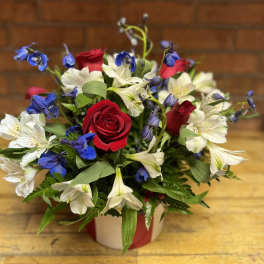 Red roses and white-blue alstroemeria in a wrapped vase arrangement
