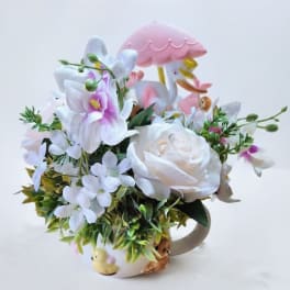 White and pink floral arrangement in a mug with a pink umbrella topper