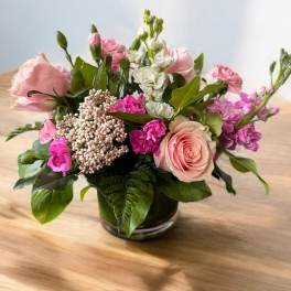 Pink and white mixed flower arrangement in a low glass vase
