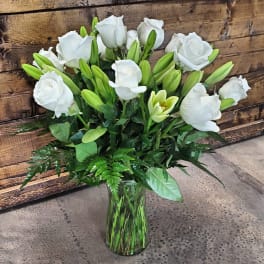 White roses and lilies arranged in a clear glass vase