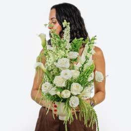Woman holding a white and green floral arrangement in a vase