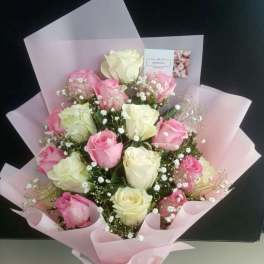 Bouquet of pink and white roses wrapped in pale pink paper