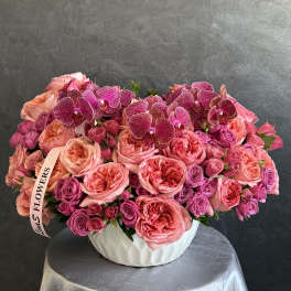 Pink roses and orchids arranged in a white vase