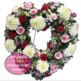 Heart-shaped floral wreath with pink roses, white mums, and red carnations