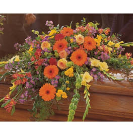 Colorful floral casket spray with orange gerberas and yellow blooms