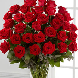 Bouquet of red roses in a clear glass vase with a box of chocolates