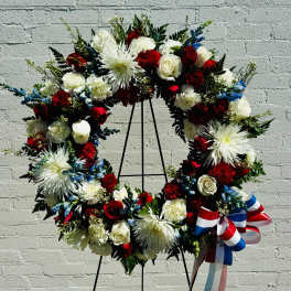 Large red, white, and blue floral wreath on a stand with ribbon
