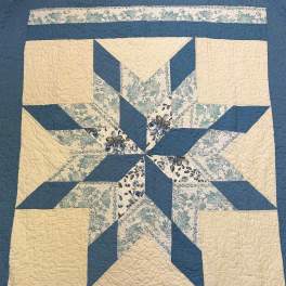 Blue and cream patchwork quilt with a star pattern